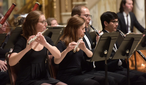 Catholic ҽ woodwind instrument players performing on stage.